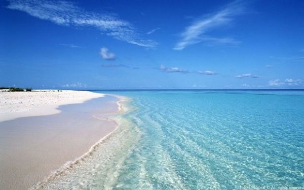 Praia com areia branca e um mar azul simplesmente paradisíaca perto de Lisboa